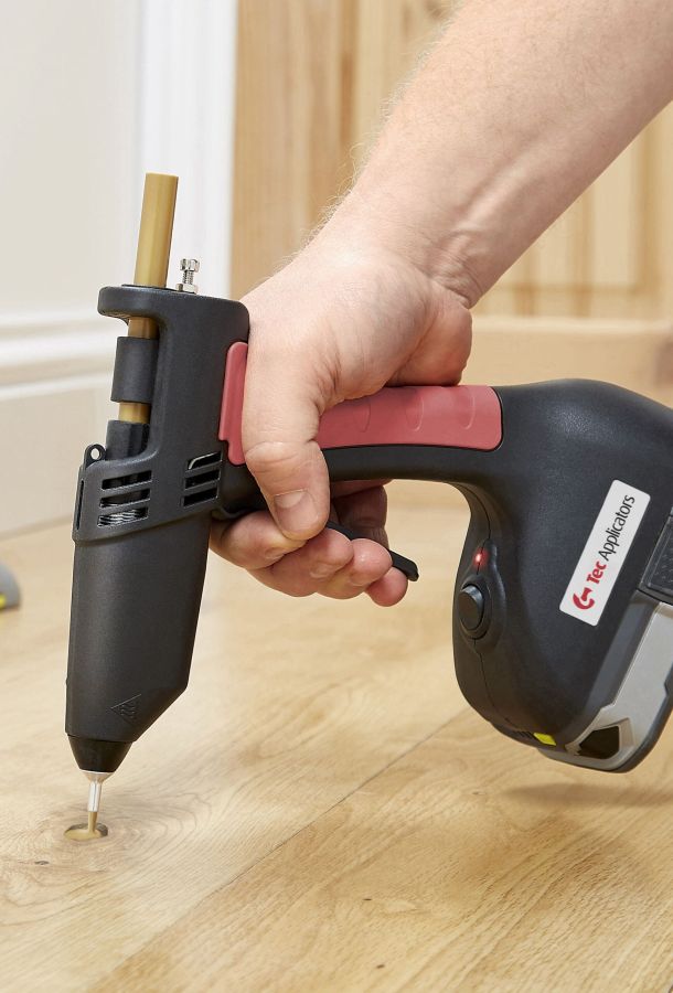 Closeup of person filling a knot in a floorboard with Knottec filling compound