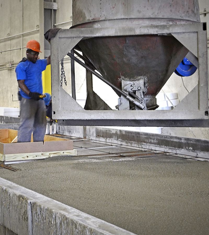 Large pouring machine dispensing concrete into a precast mould