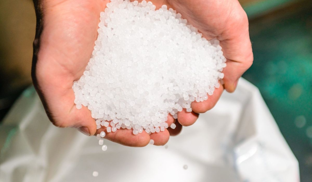 White plastic grain, plastic polymer granules in a persons hand