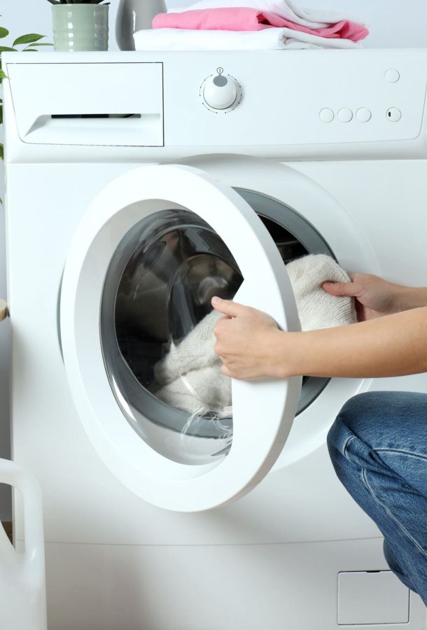Lady putting dirty clothes into a washing machine