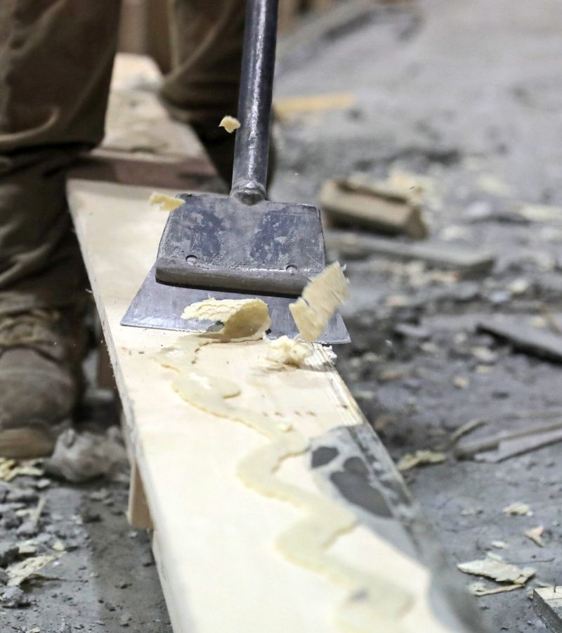 Crystalised Casttec adhesives being scrapped off a wooden panel