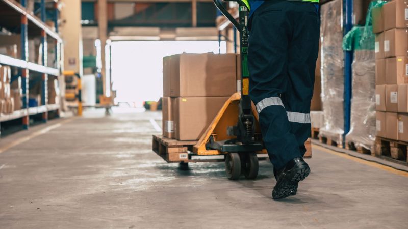 Warehouse staff moving load parcel box with Hand pallet truck