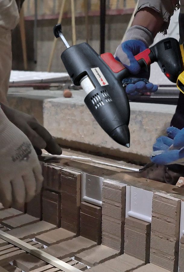 Workers using cordless Tec glue gun to attach insert pieces to the framework of a concrete precast form