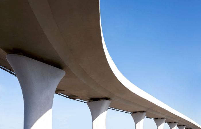 Section of concrete bridge extending out of frame. Blue sky in background