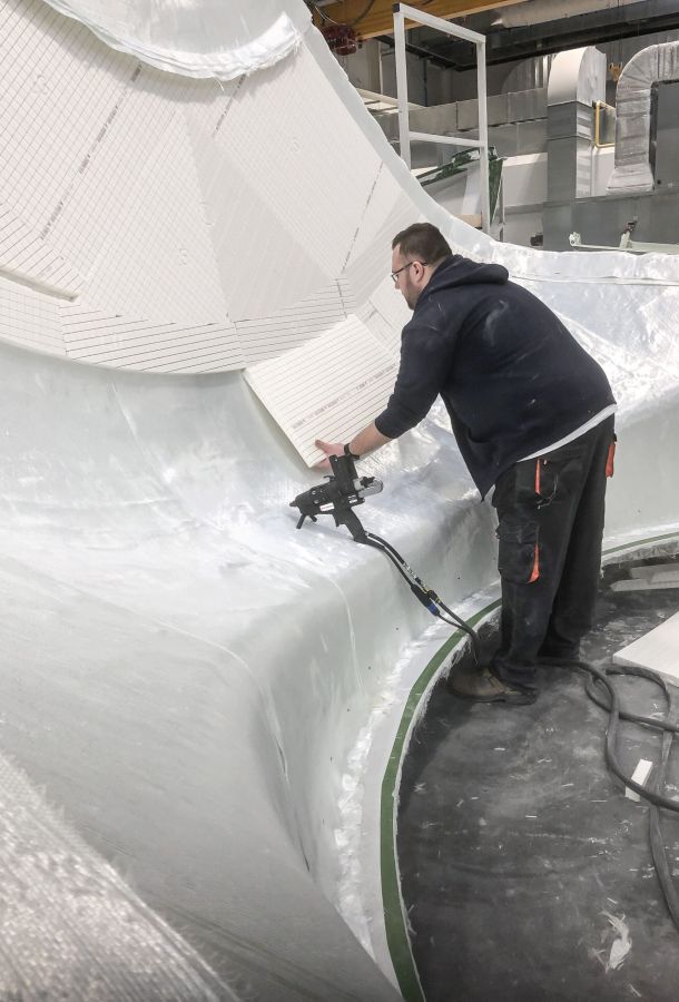 Man applying GRP foam to fiberglass hull of boat using hot melt adhesive