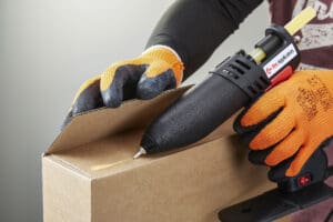 Person using Tecbond 214B to seal a carboard box.