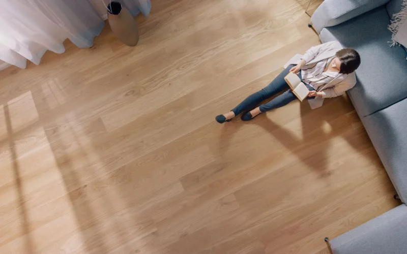 Young woman is sitting on a floor and reading a book